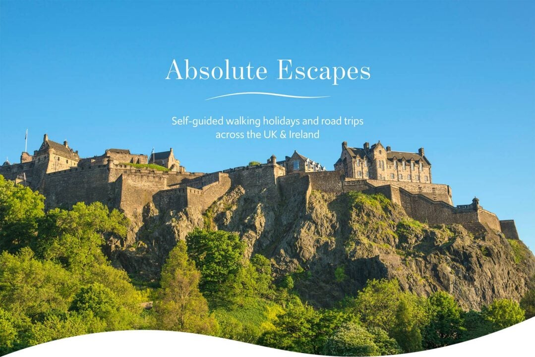 Edinburgh Castle from Princes Street, on a sunny day with blue skies. Text on the image reads: 'Absolute Escapes. Self-guided walking holidays and road trips across the UK & Ireland.',© Visit Scotland, Kenny Lam