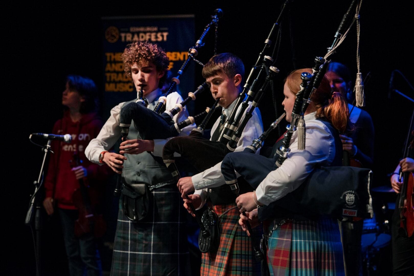 3 people in kilts playing the bagpipes.