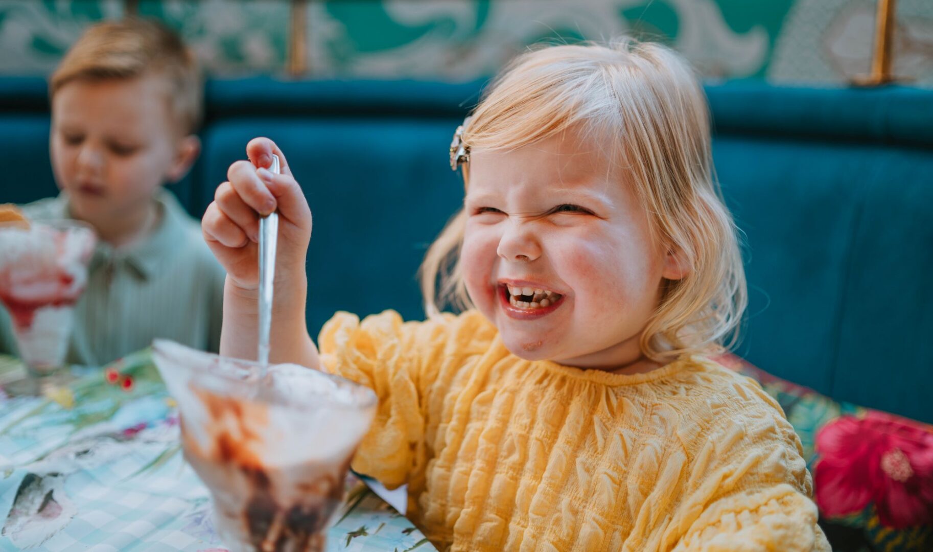 A young girl eating an ice cream and smiling.