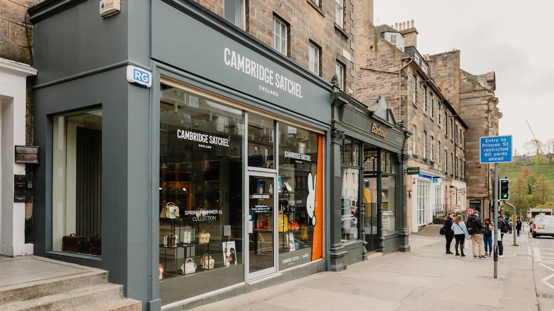 A modern storefront with wide glass windows and the name of the shop 'Cambridge Satchel' in white lettering over the doorway.