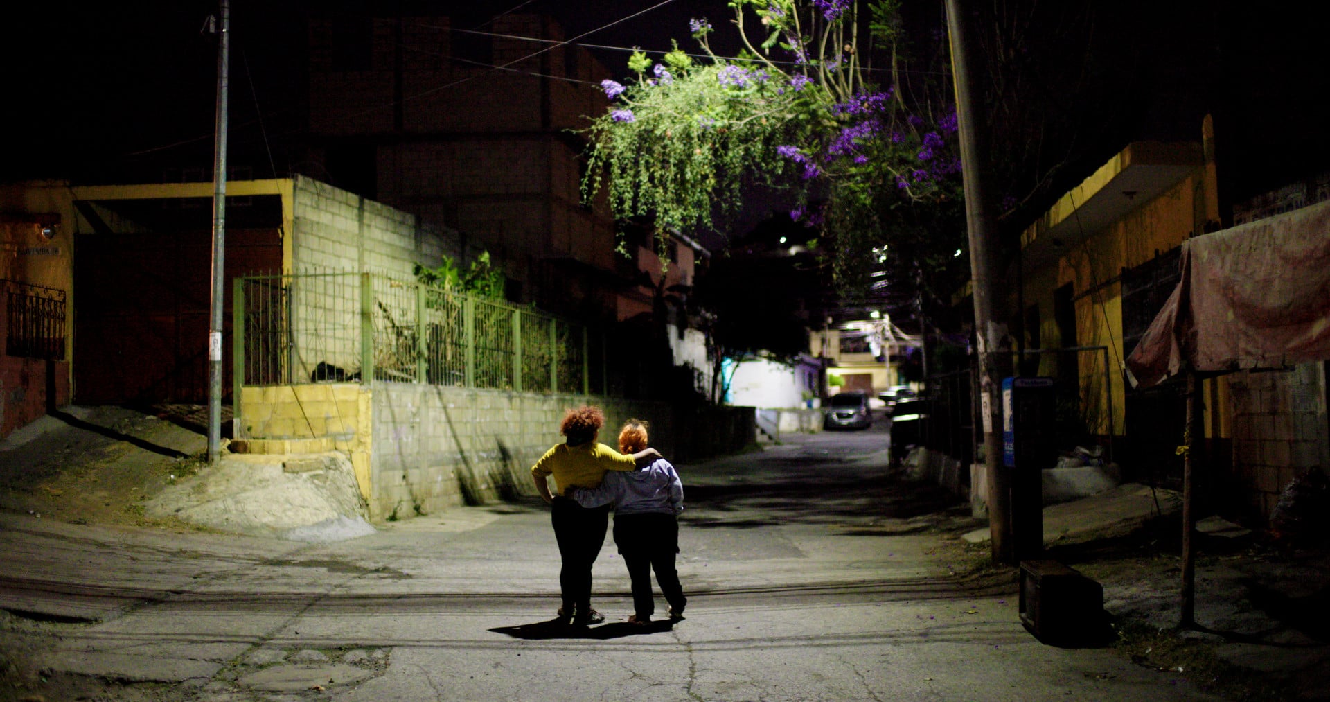 2 people walking through a deserted street at night.