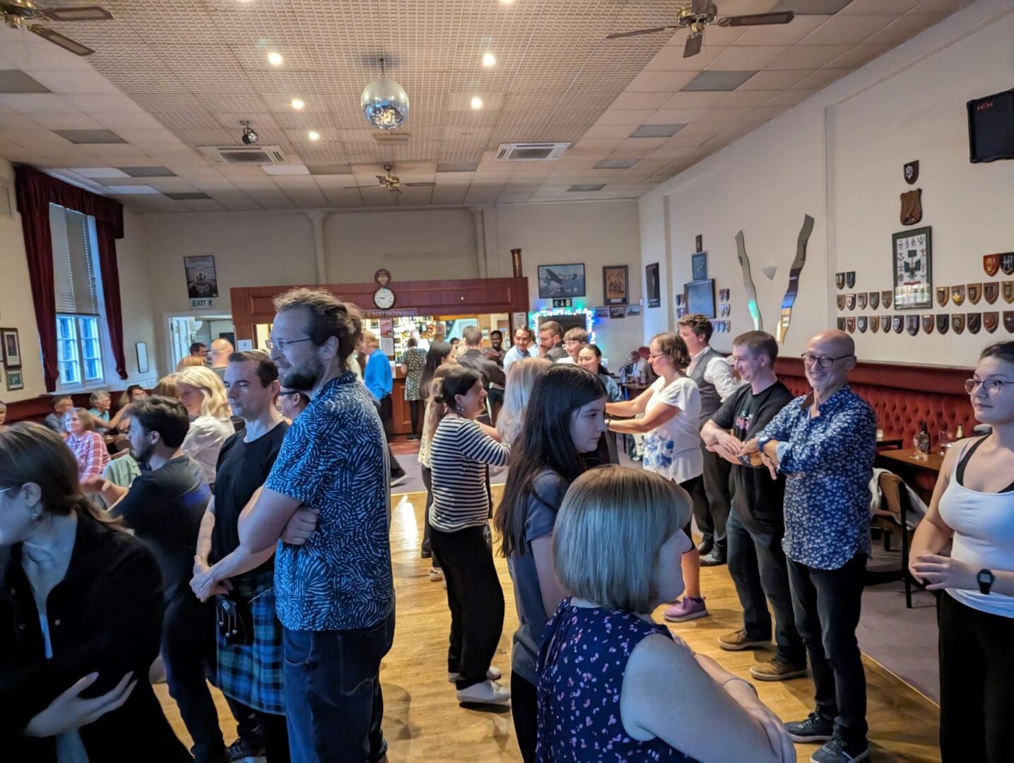 A room full of people, standing in lines, with arms crossed in front of them.