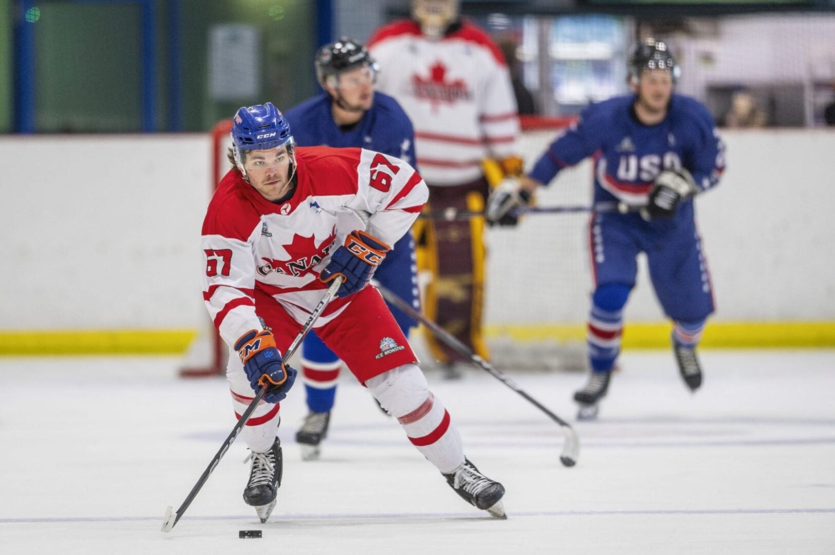 3 people on an ice rink, playing ice hockey.