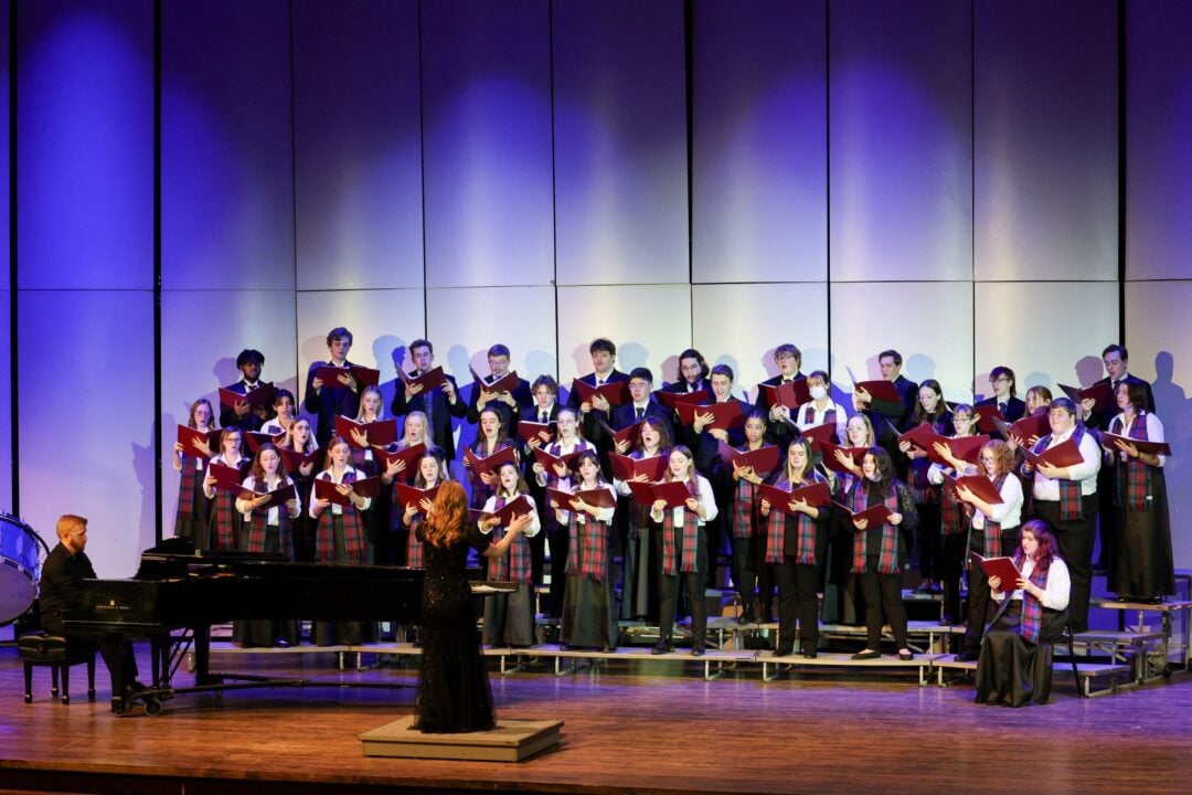 A group of people standing on a stage, singing.