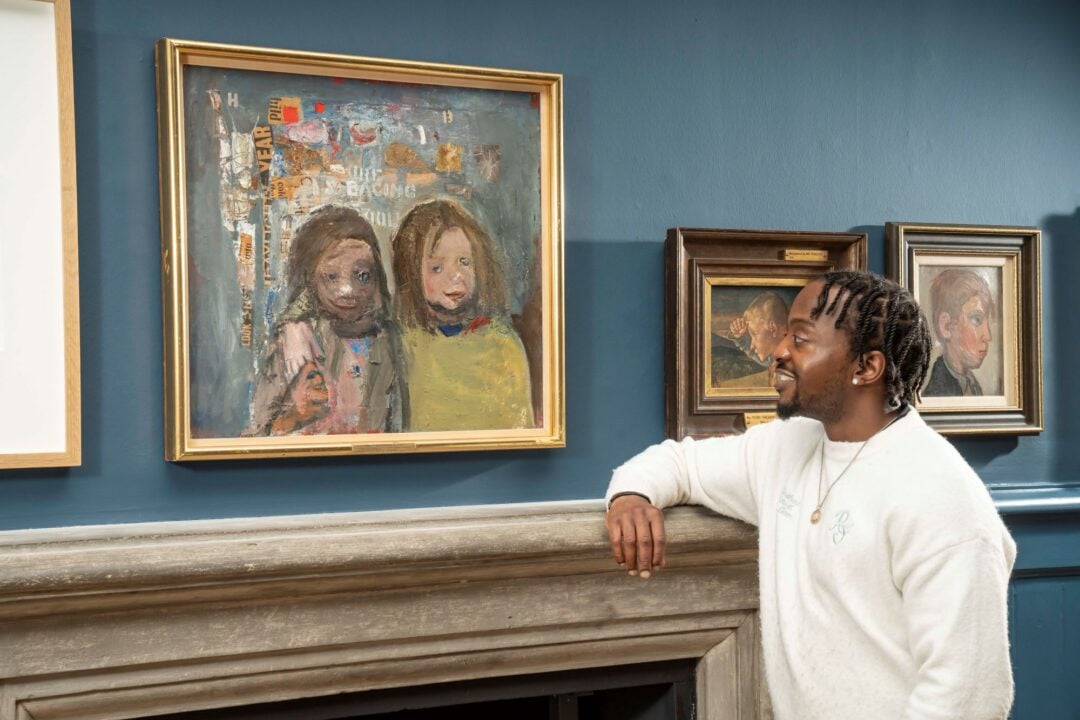 A man looks at a painting on a wall of 2 small girls.