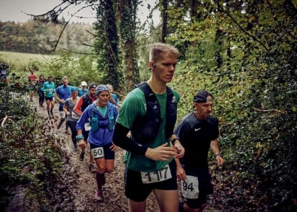 A group of people running through a wooded area.