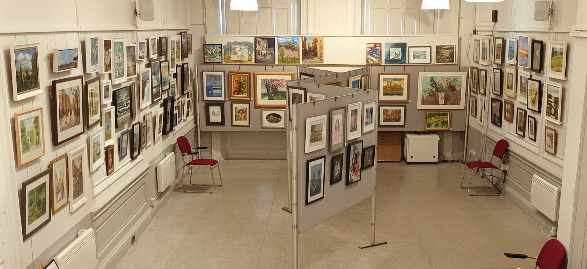 A room full of paintings hung on the walls.