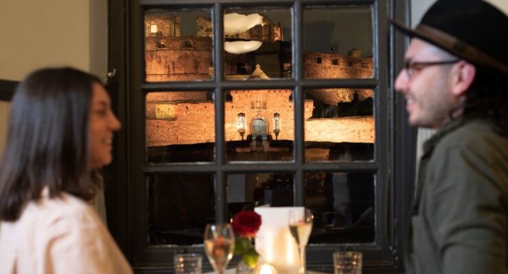 two people dining at Cannonball Restaurant with Edinburgh Castle visible through the window.