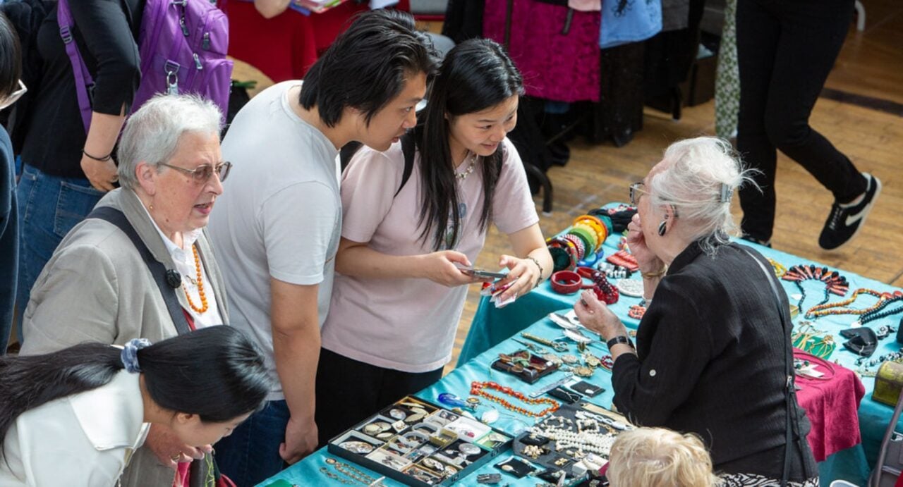 People at a stall, which has a variety of jewellery items.