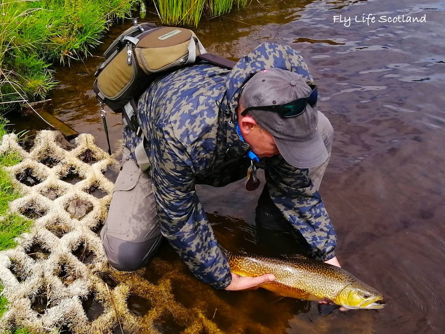 Man putting fish back in water after catching it with Fly Life Scotland Tours