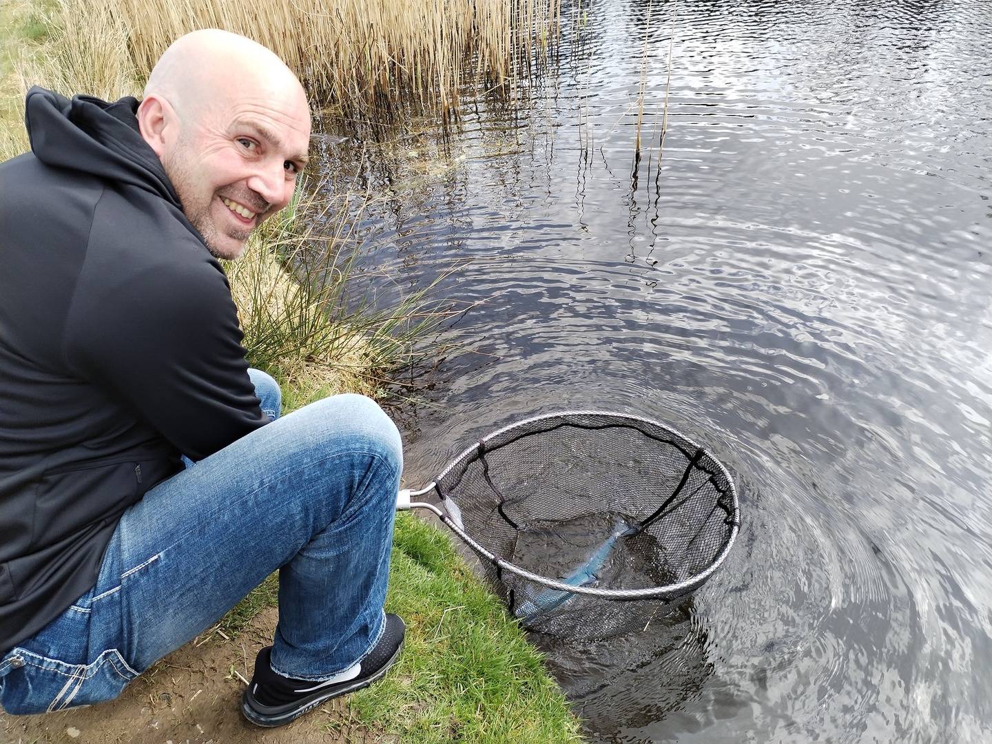Man with fish in net with Fly Life Scotland Tours