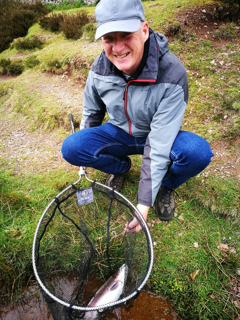 Man with fish in net with Fly Life Scotland Tours
