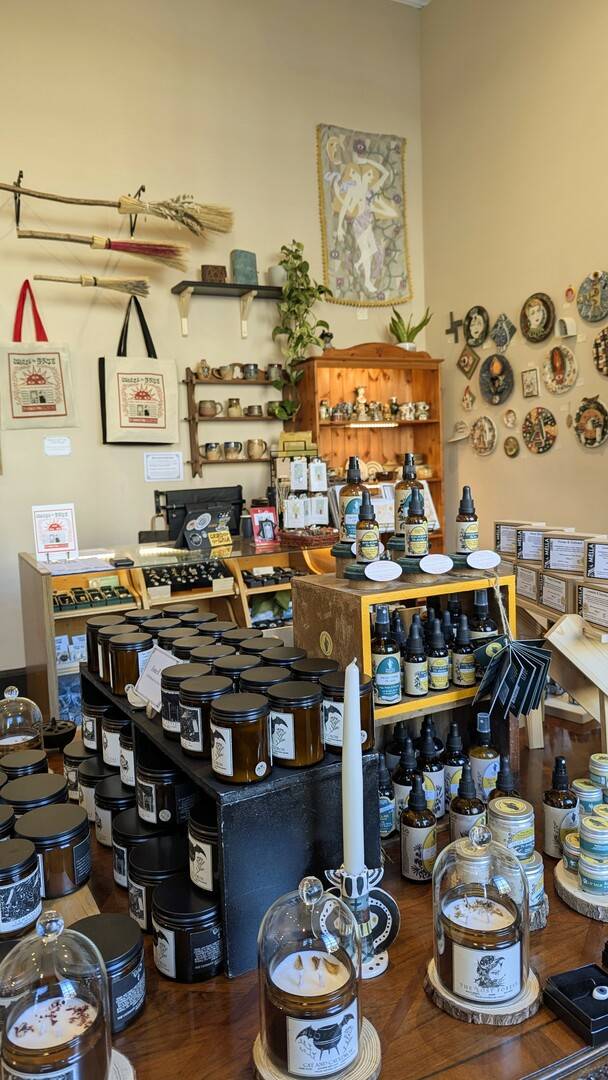 a sunny room showing candles, skincare products, ceramic pieces, art, and witches brooms