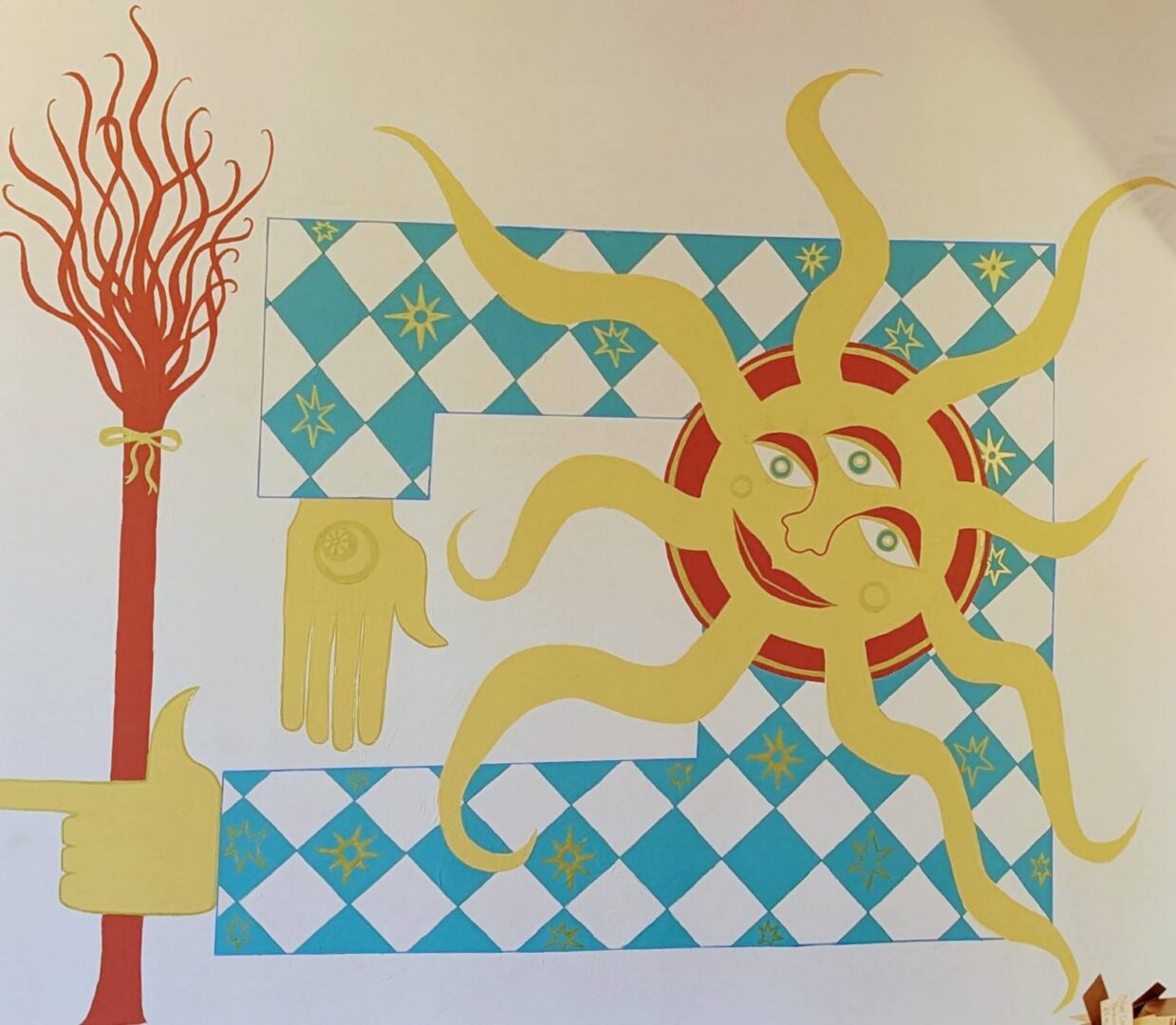 a sunny room with a harlequin-patterned sun mural. The sun holds a witch's broom in its hand