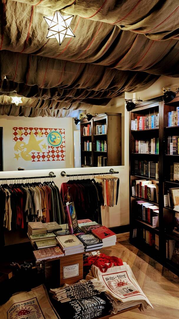 A cosy, fabric-draped room with books, t-shirts, and a harlequin moon mural