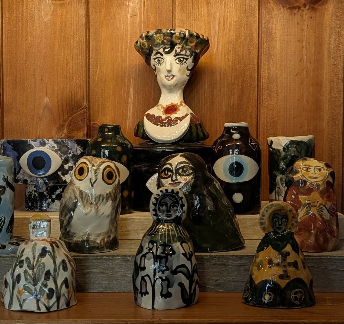 a display of ceramic pieces, with motifs including owls, eyes, witches, and suns.