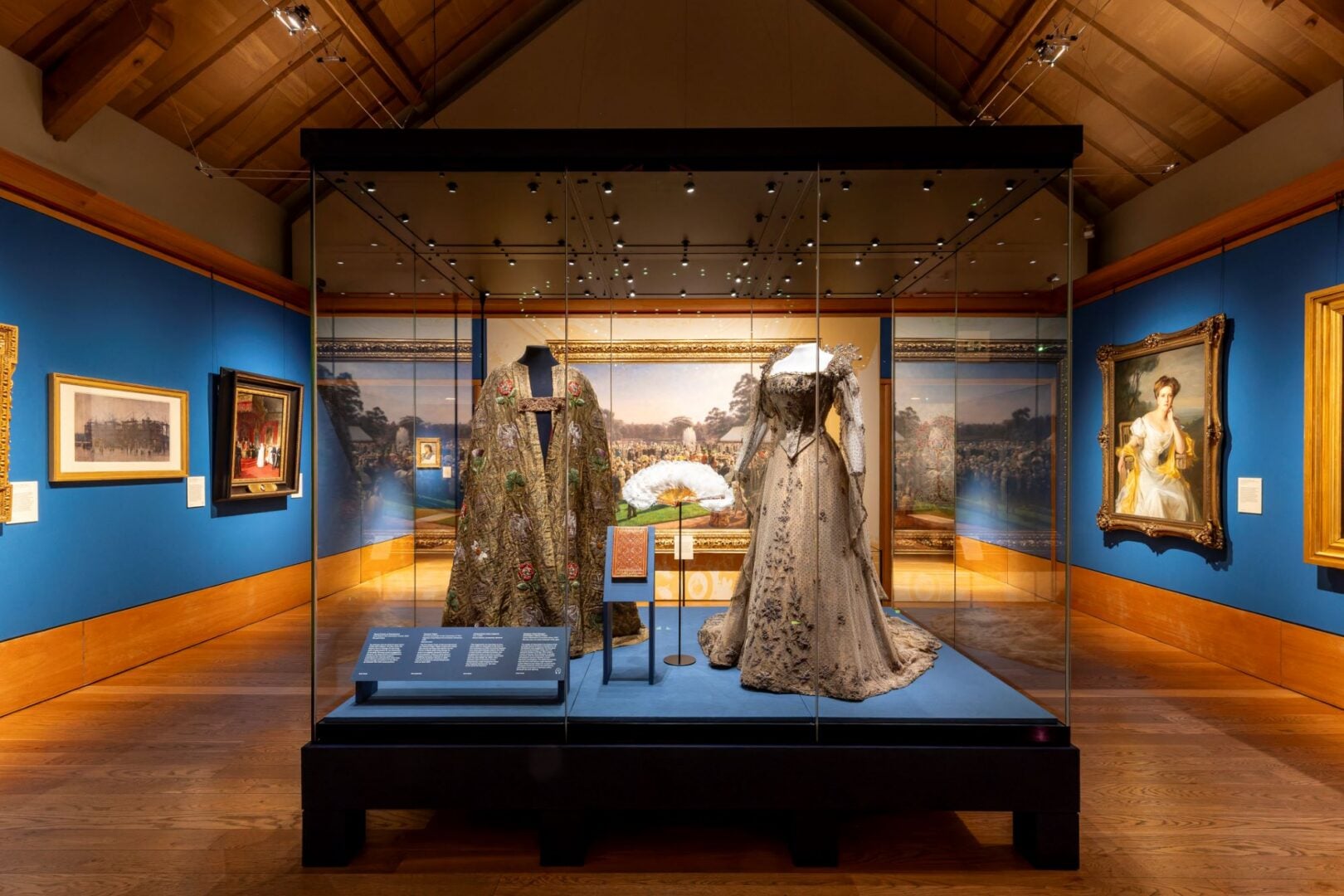 A regal cloak and dress in a glass cabinet.