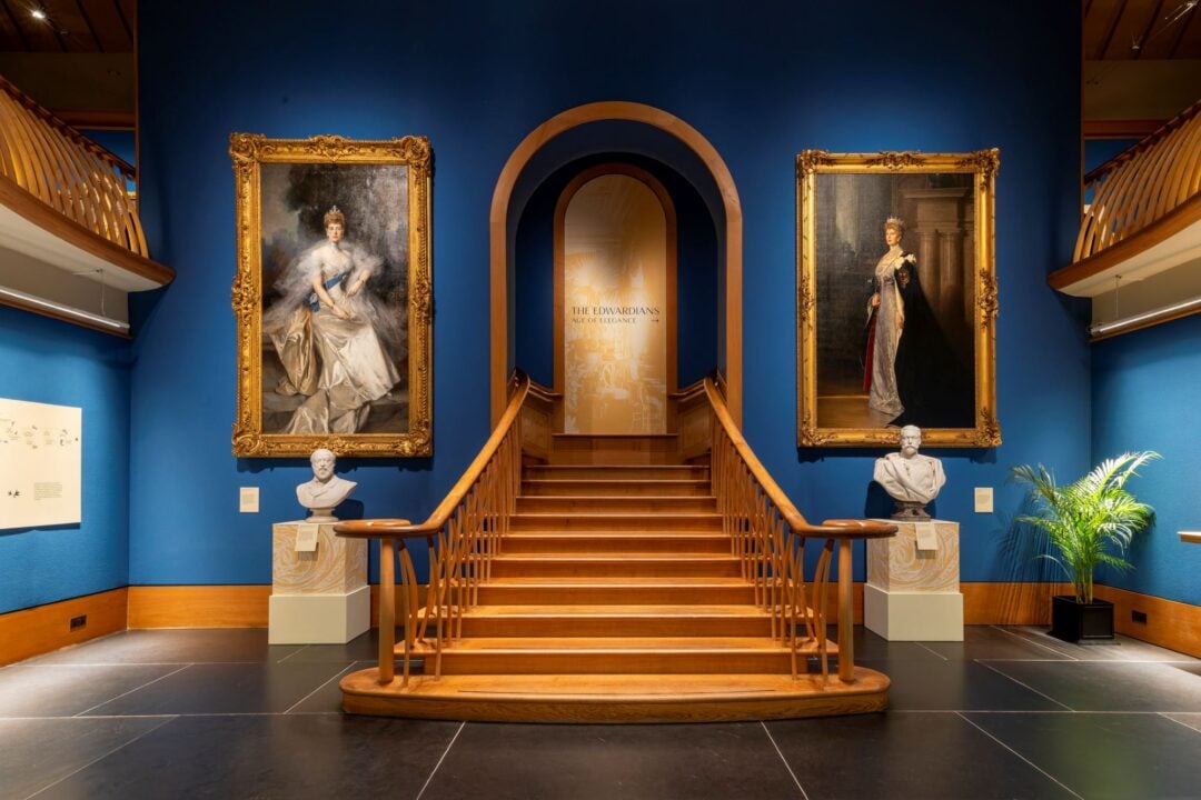 A staircase, with a painting of a lady in regal dress on either side.