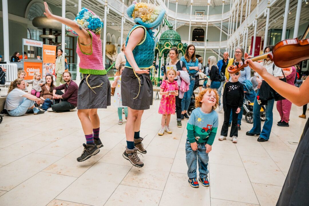 A group of young children watching musicians and performers.