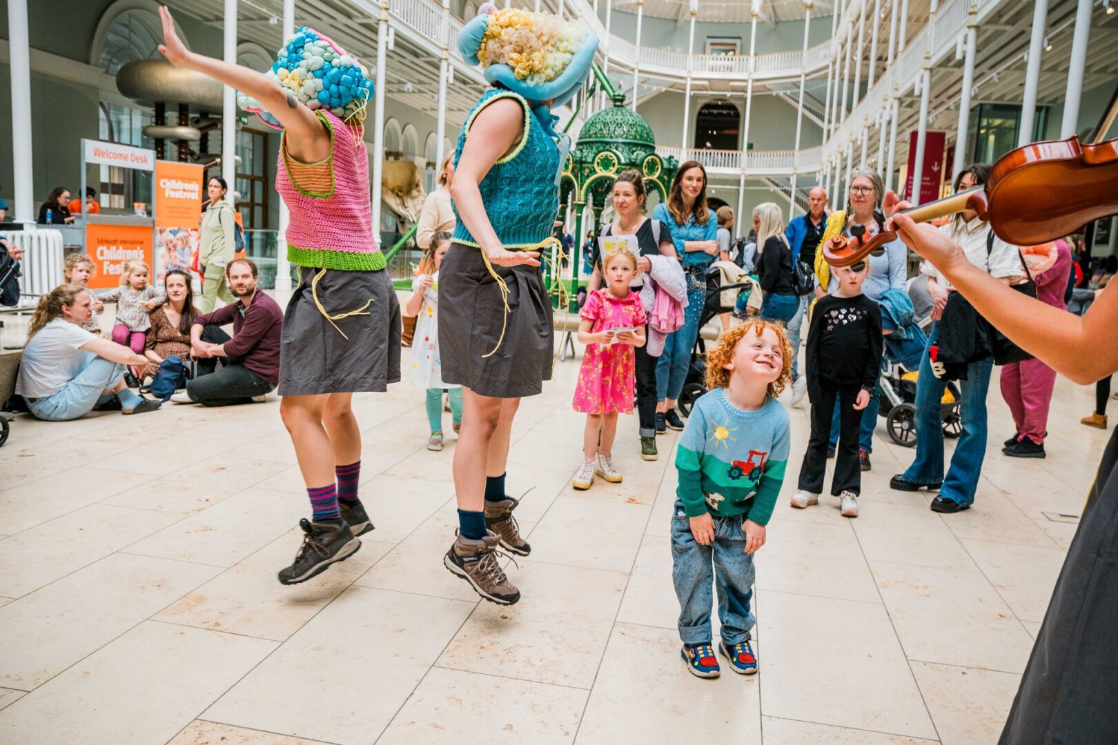 A group of young children watching musicians and performers.