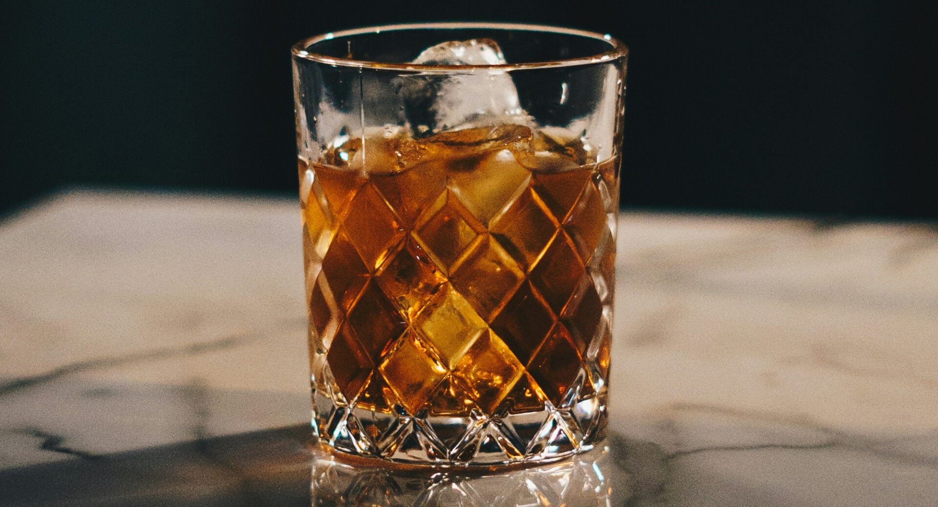 A glass filled with whisky and ice cubes.