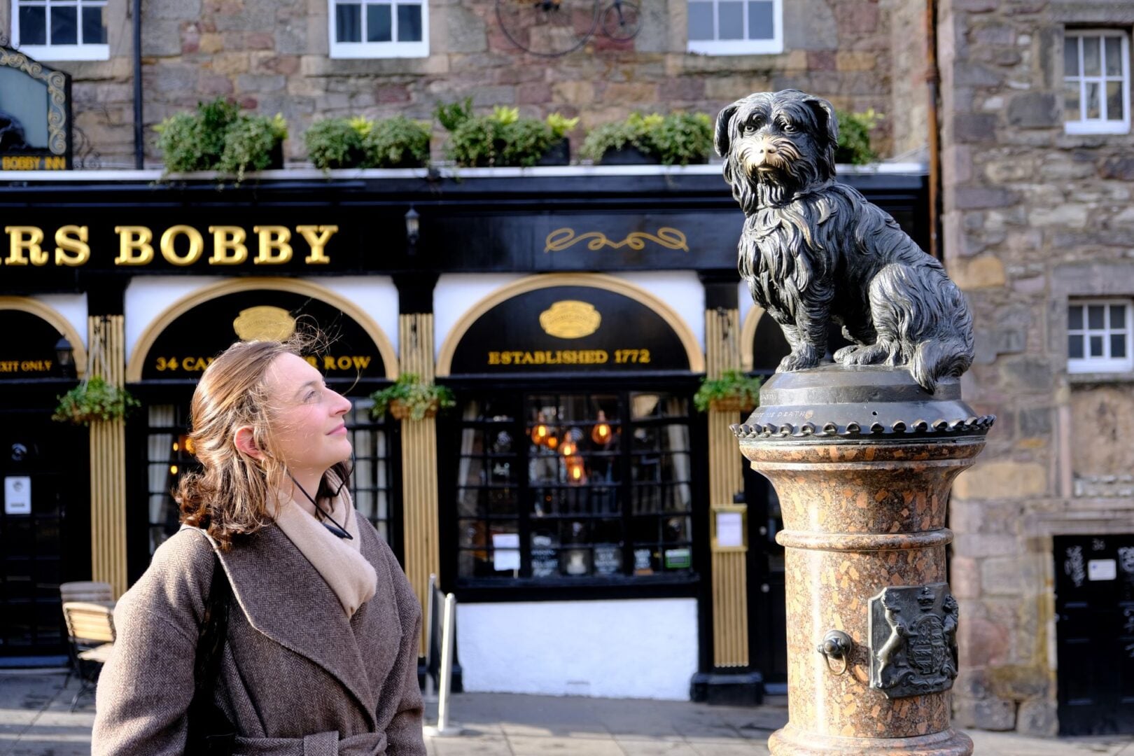 A woman looking at a statue of a small dog.