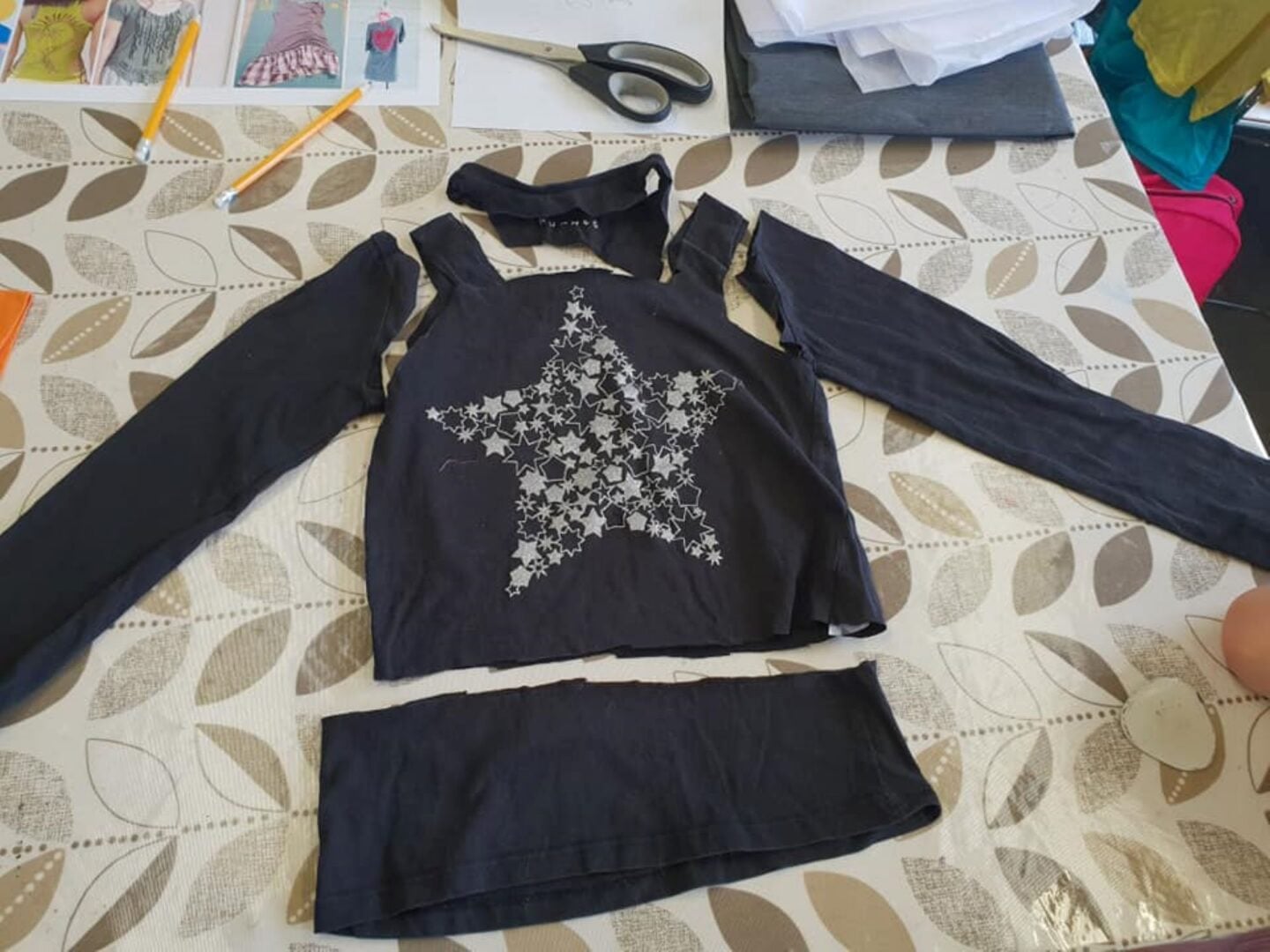 A long sleeve top with a silver star lying on a worksurface.