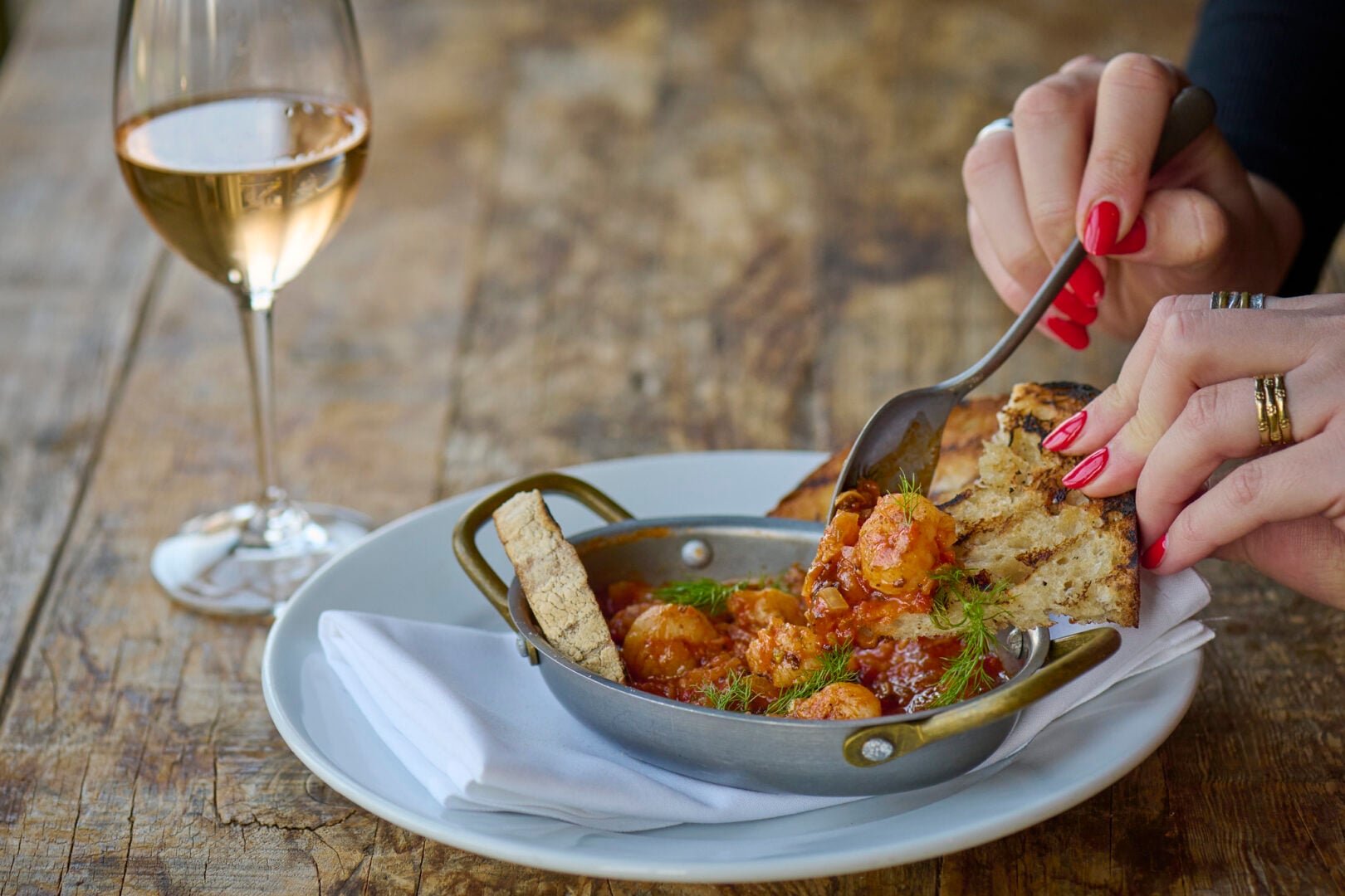a person's hand with fork eating food at Hotel du Vin