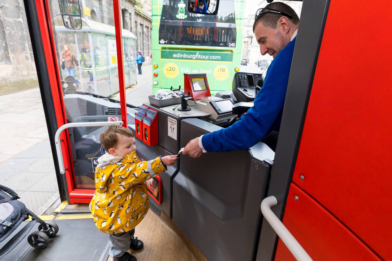 A young child handing the tour bus driver a ticket for the bus.,© Edinburgh Bus Tours