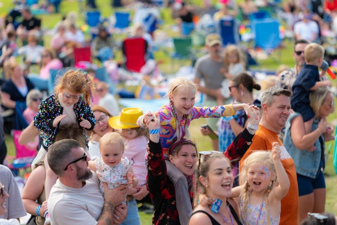 Adults and young children dancing in a large outdoor area.