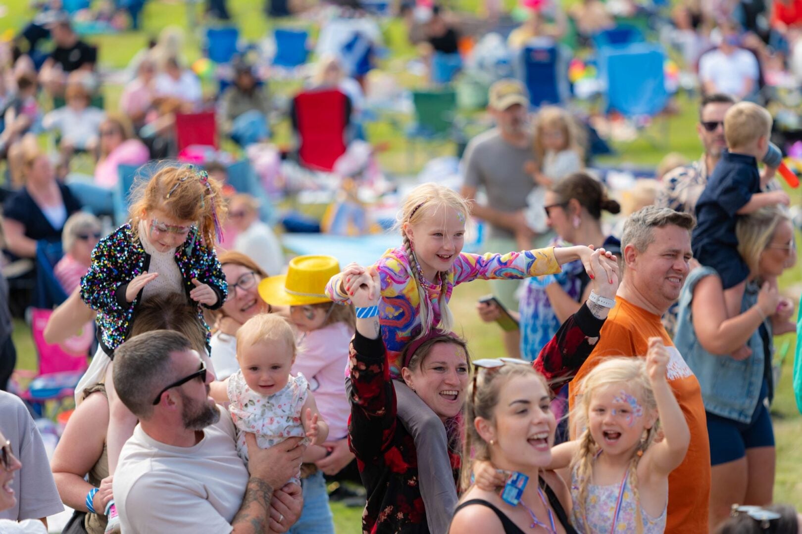 Adults and young children dancing in a large outdoor area.