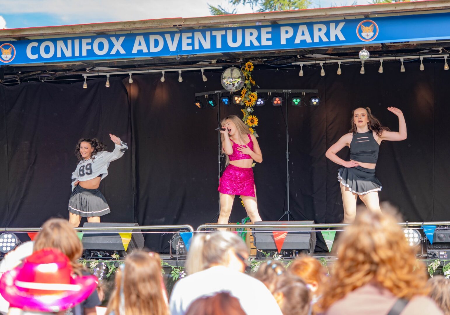 3 performers dancing on an outdoor stage.