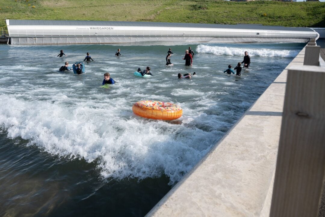 People splashing about in a large outdoor wave pool.