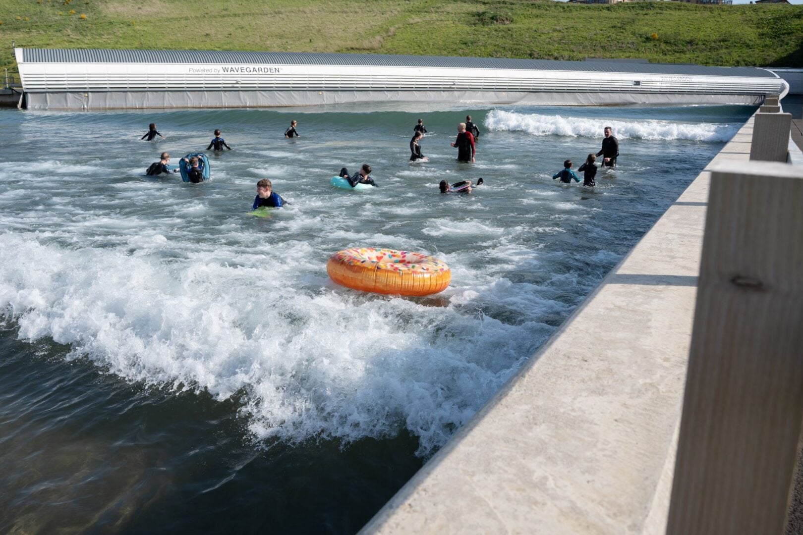 People splashing about in a large outdoor wave pool.