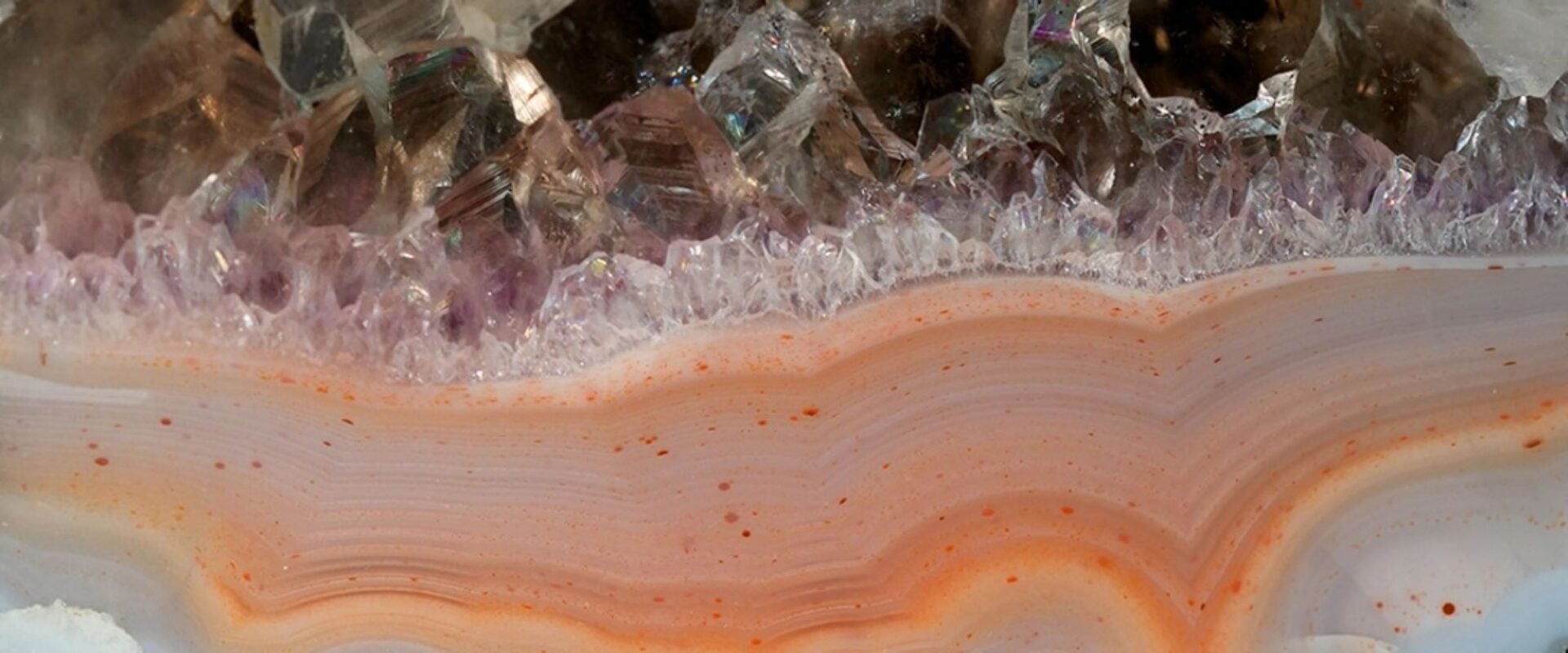 Close-up of layers of rock, in shades of orange, cream and purple.