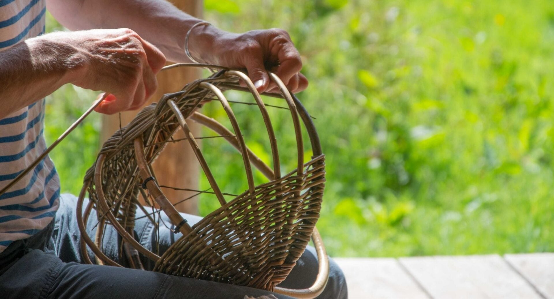 Close-up of a person weaving a basket out of willow.