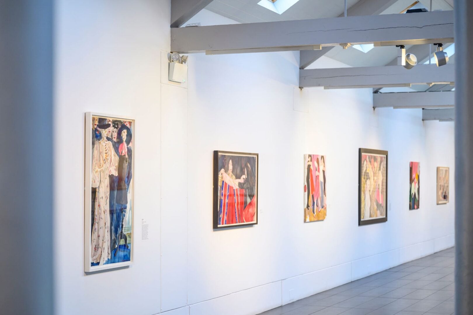 A line of paintings, hanging on a wall.