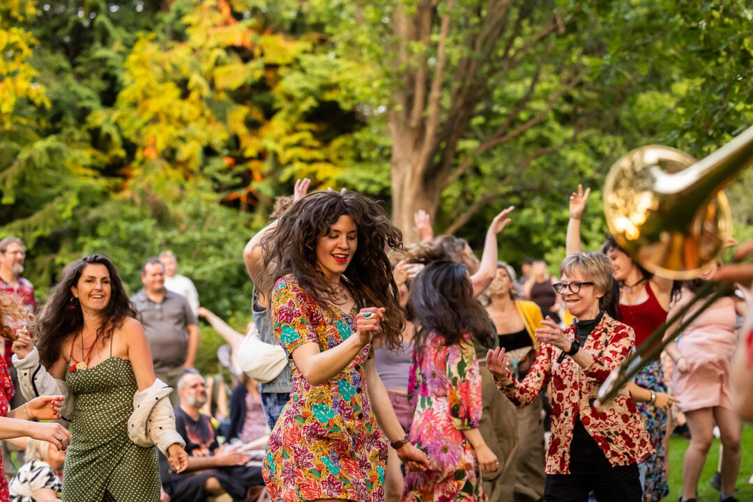 A group of people dancing amongst trees.