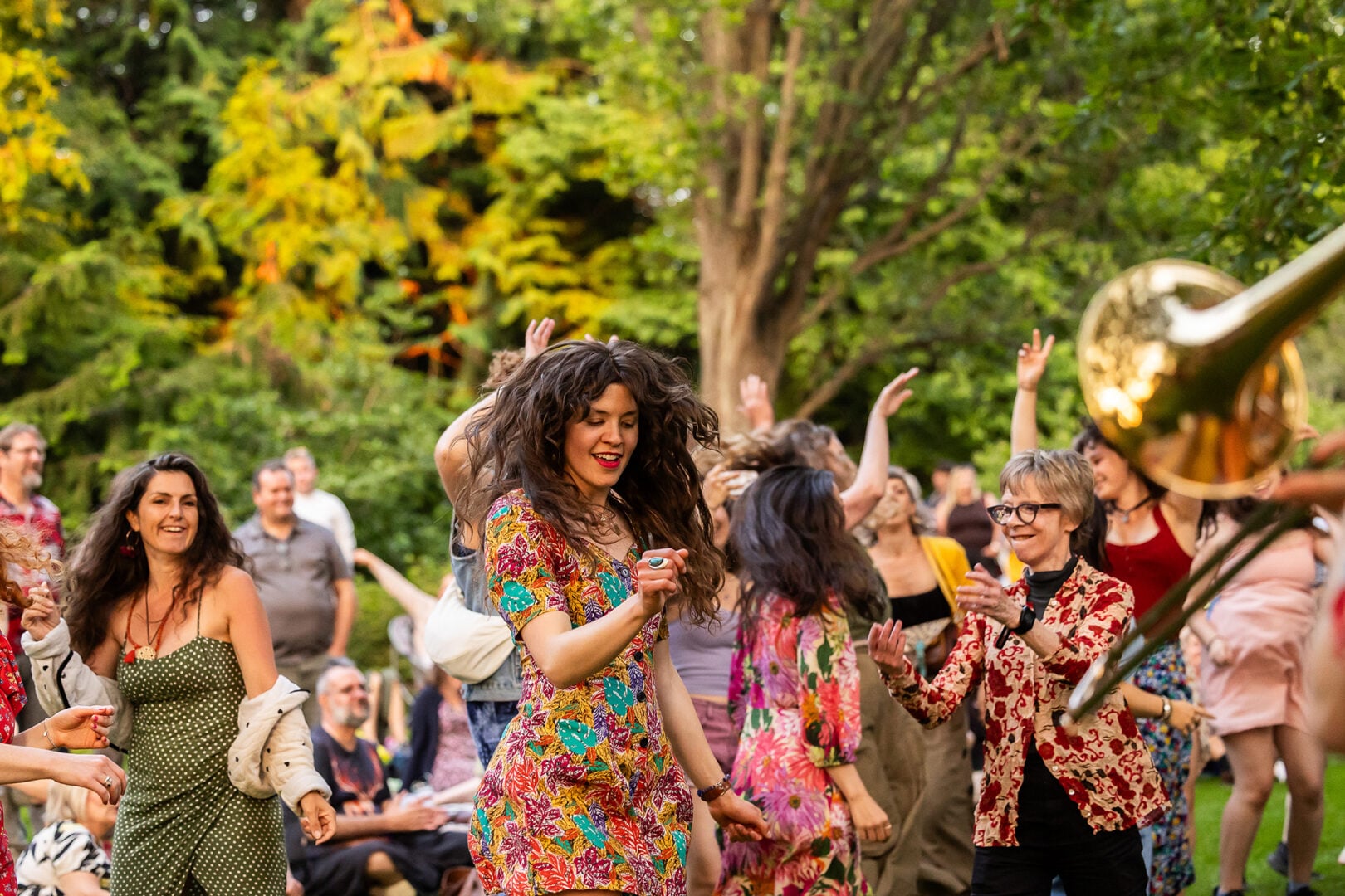 A group of people dancing amongst trees.
