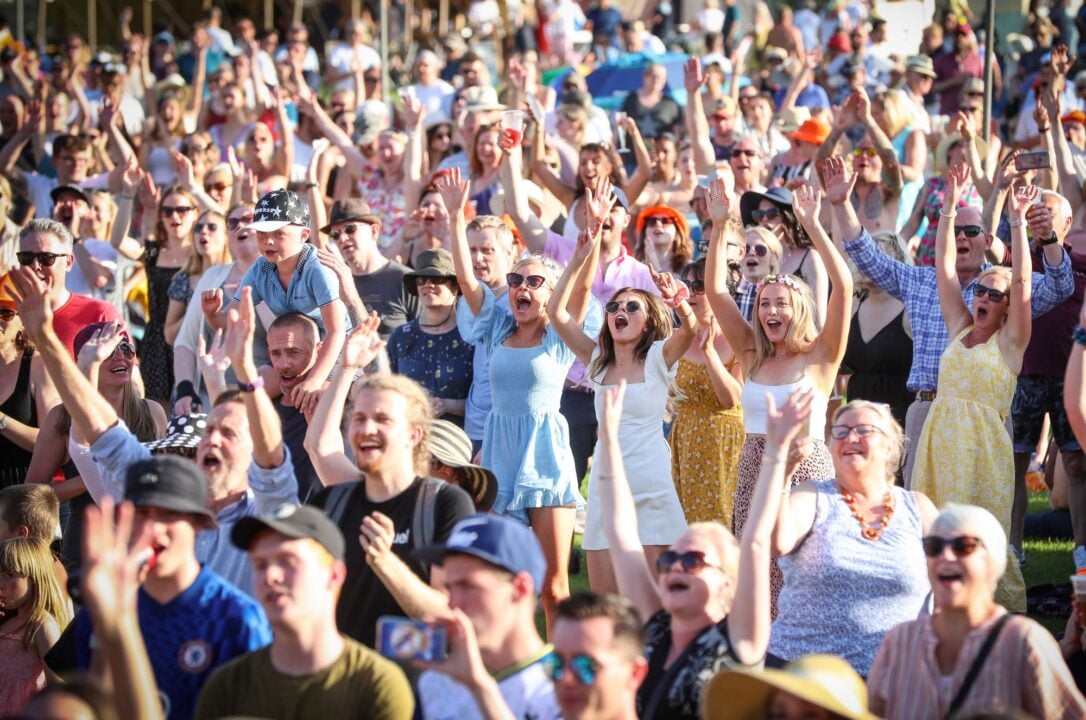 A crowd of people, outdoors, waving and cheering.