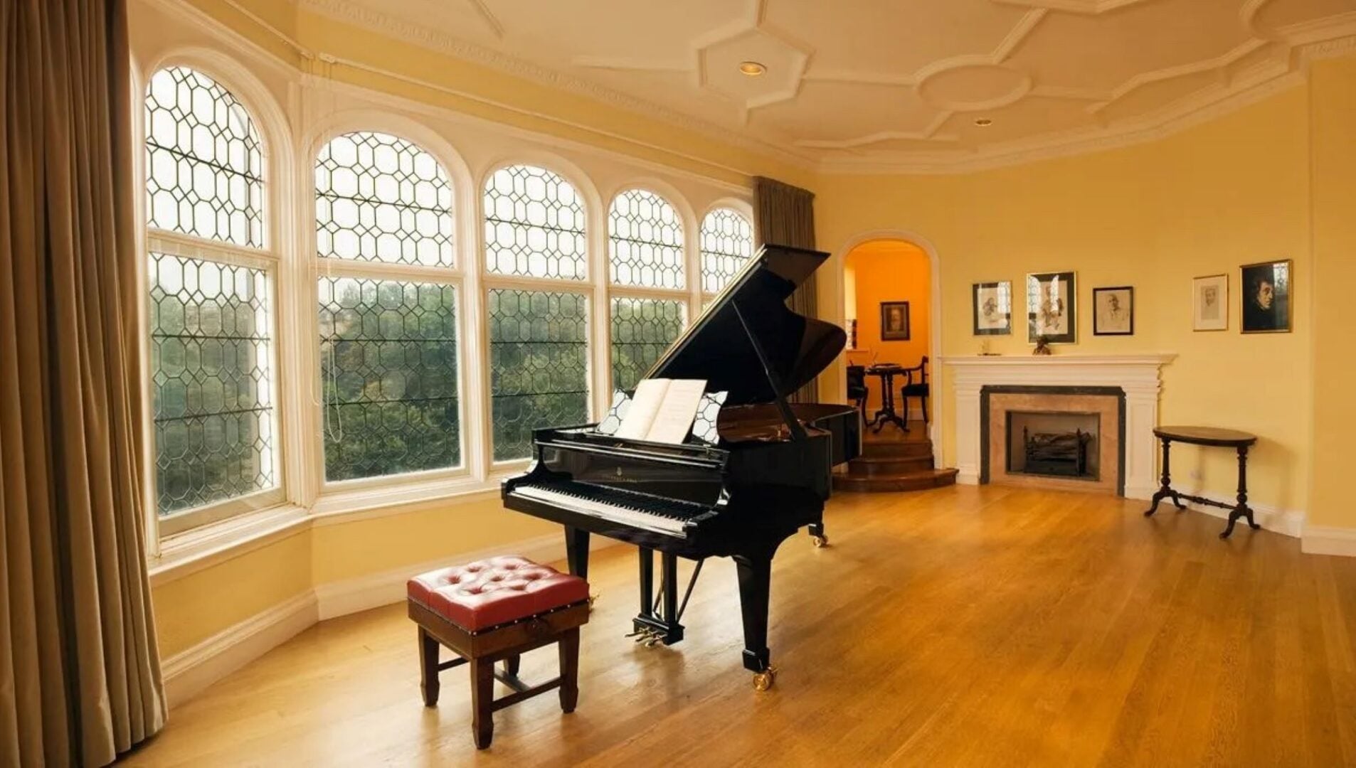 A room, with grand piano, and large stained glass windows.