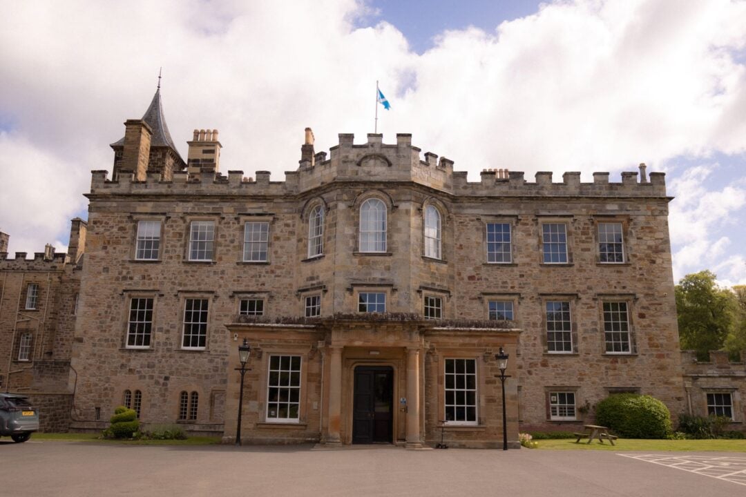 A large, grand stone building, set in leafy grounds.