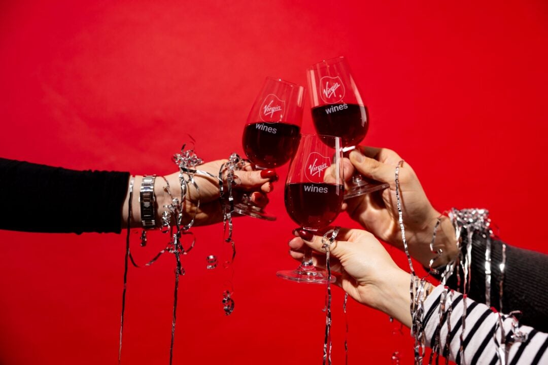 3 hands clinking glasses of red wine.