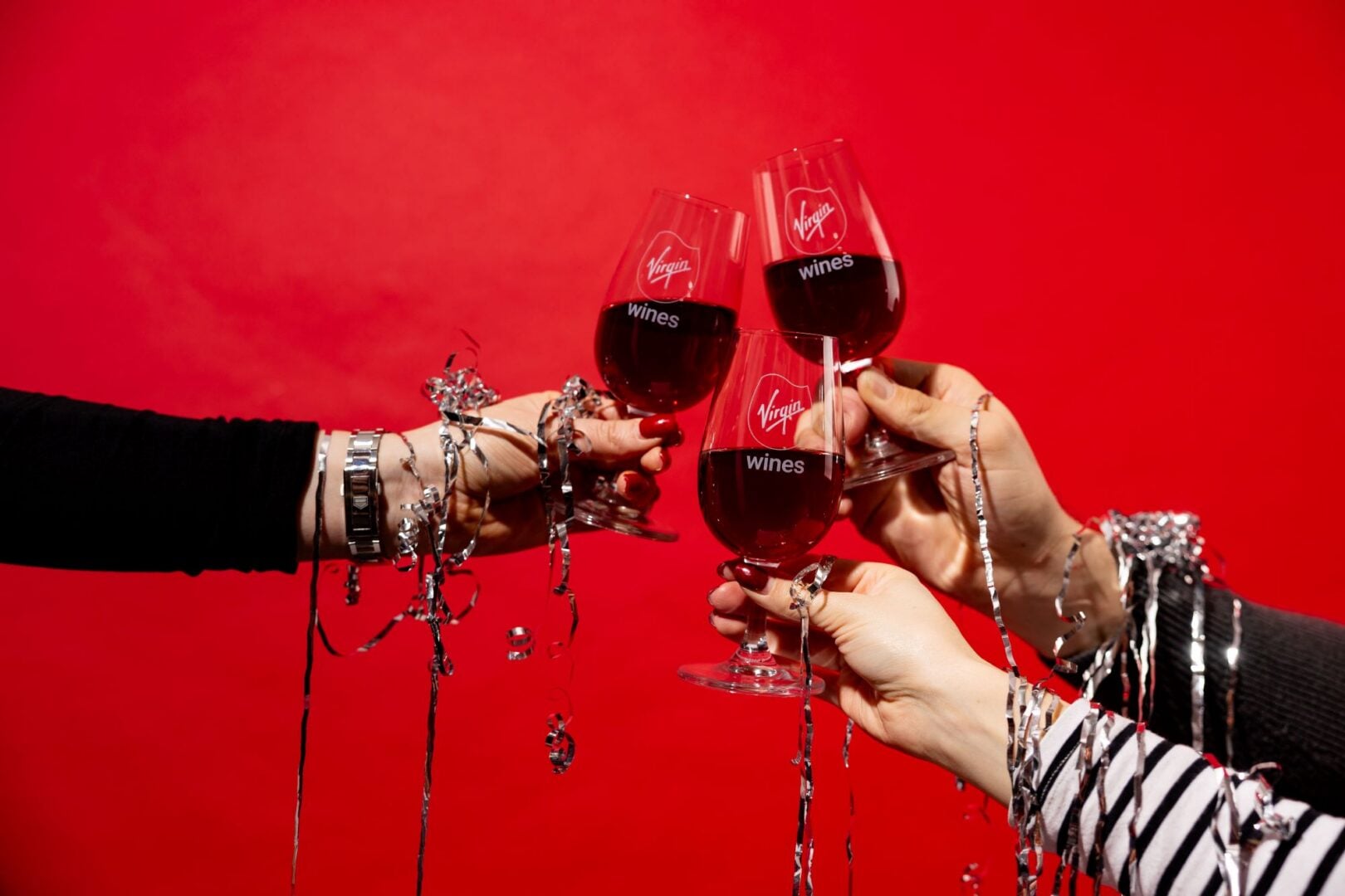 3 hands clinking glasses of red wine.