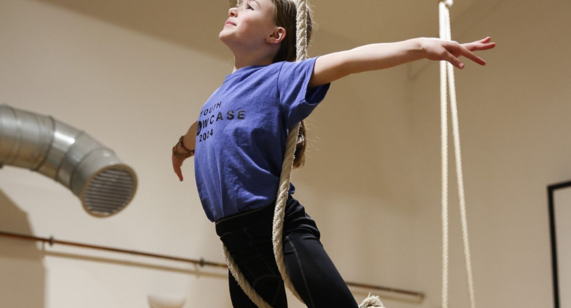 A young girl balancing on a rope.