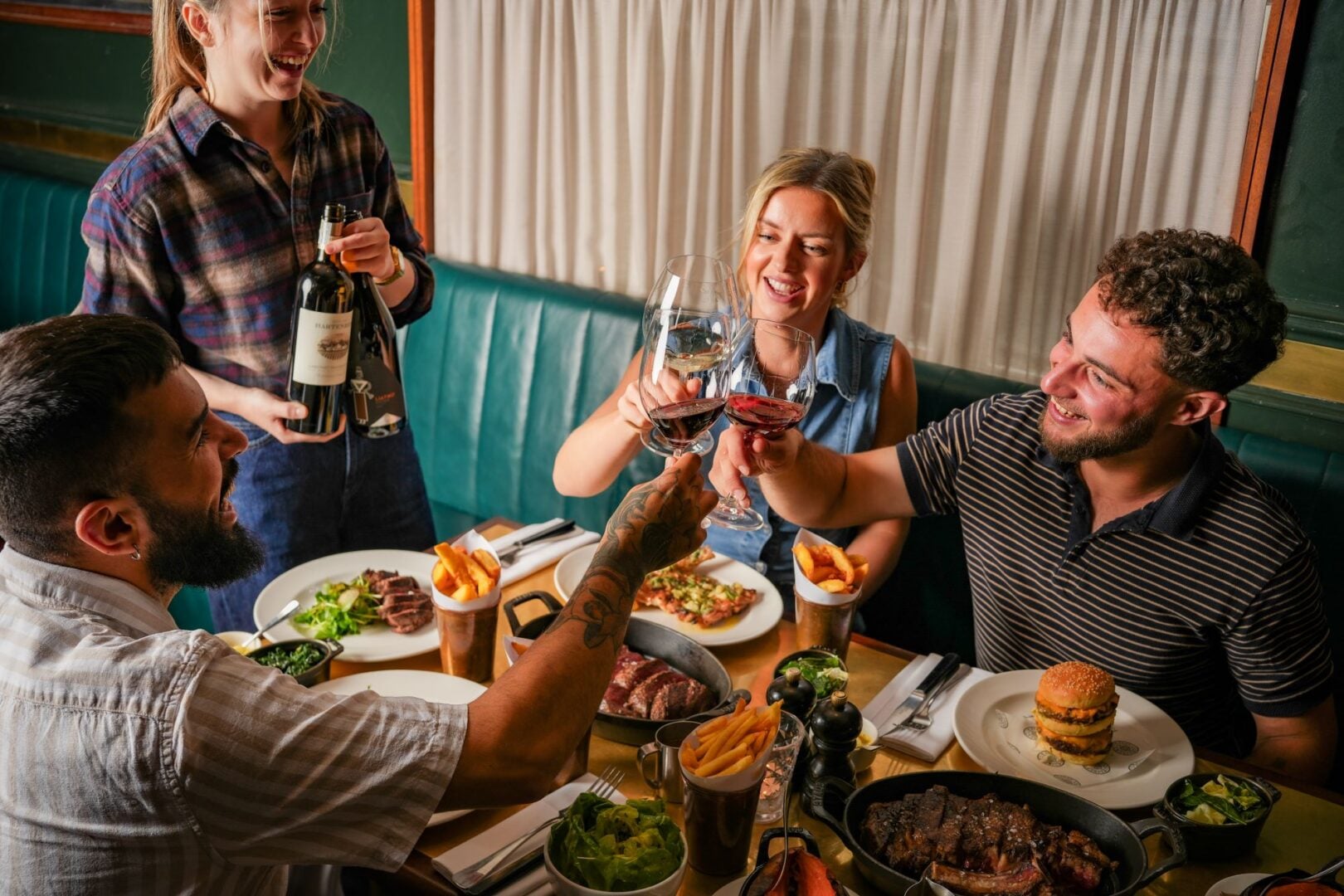 3 people seated at a table clicking wine glasses.