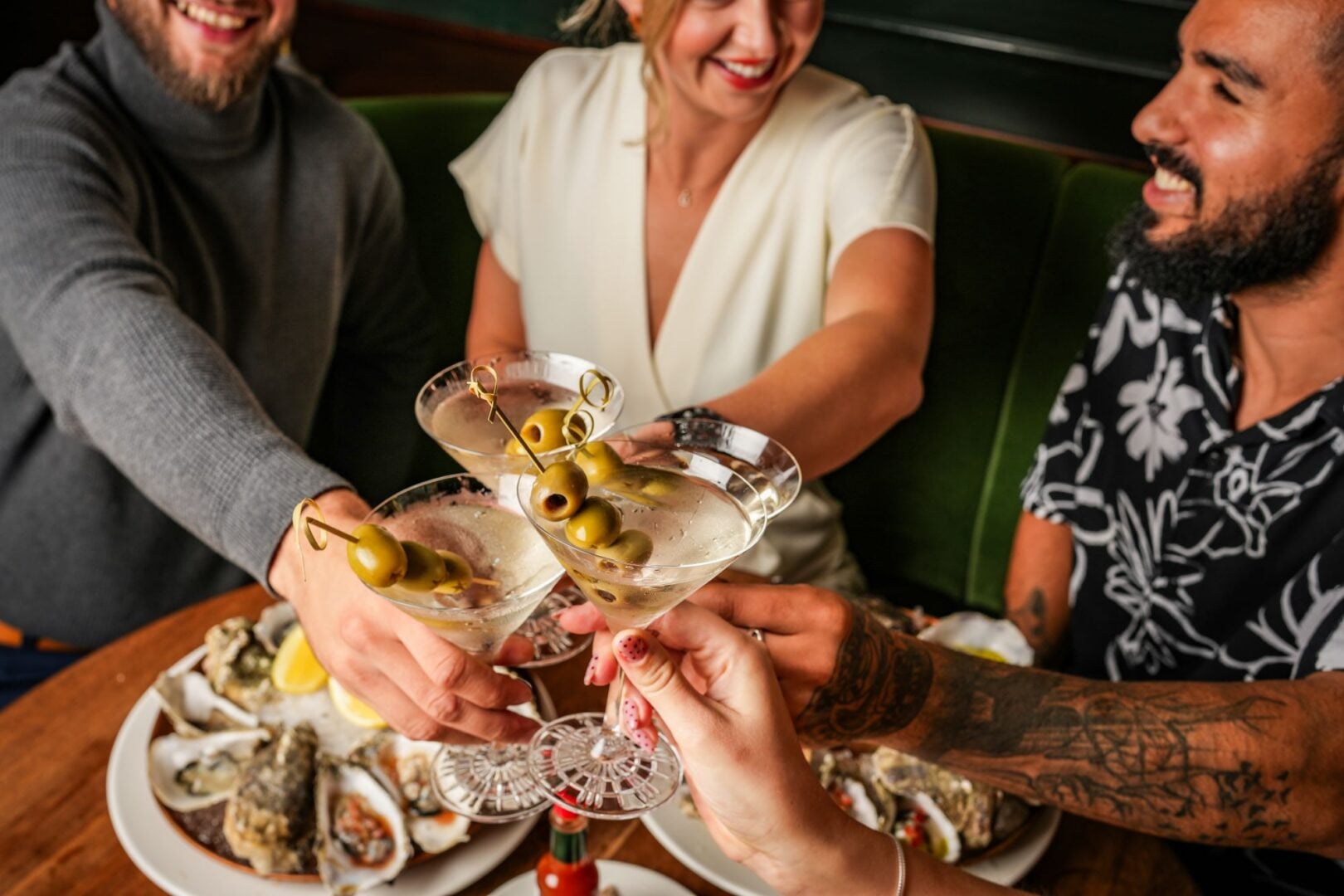 3 people round a table, clinking cocktail glasses.