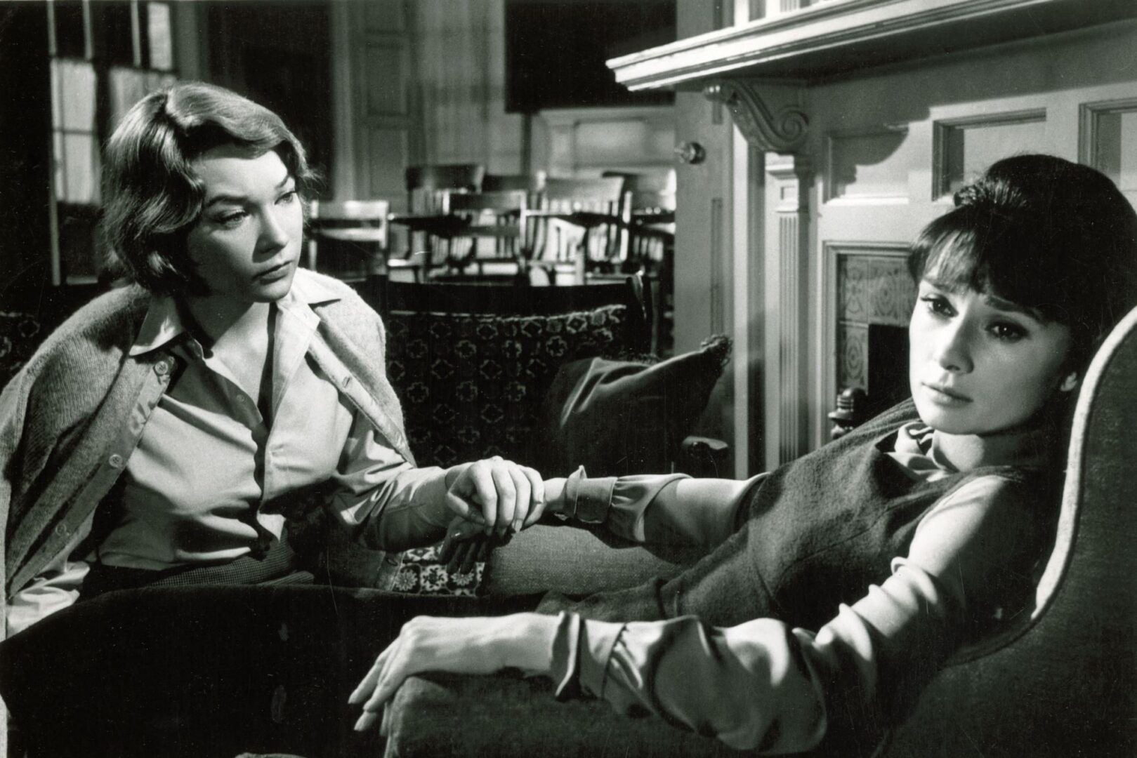 Black and white image of 2 seated woman, one of whom looks very sad.