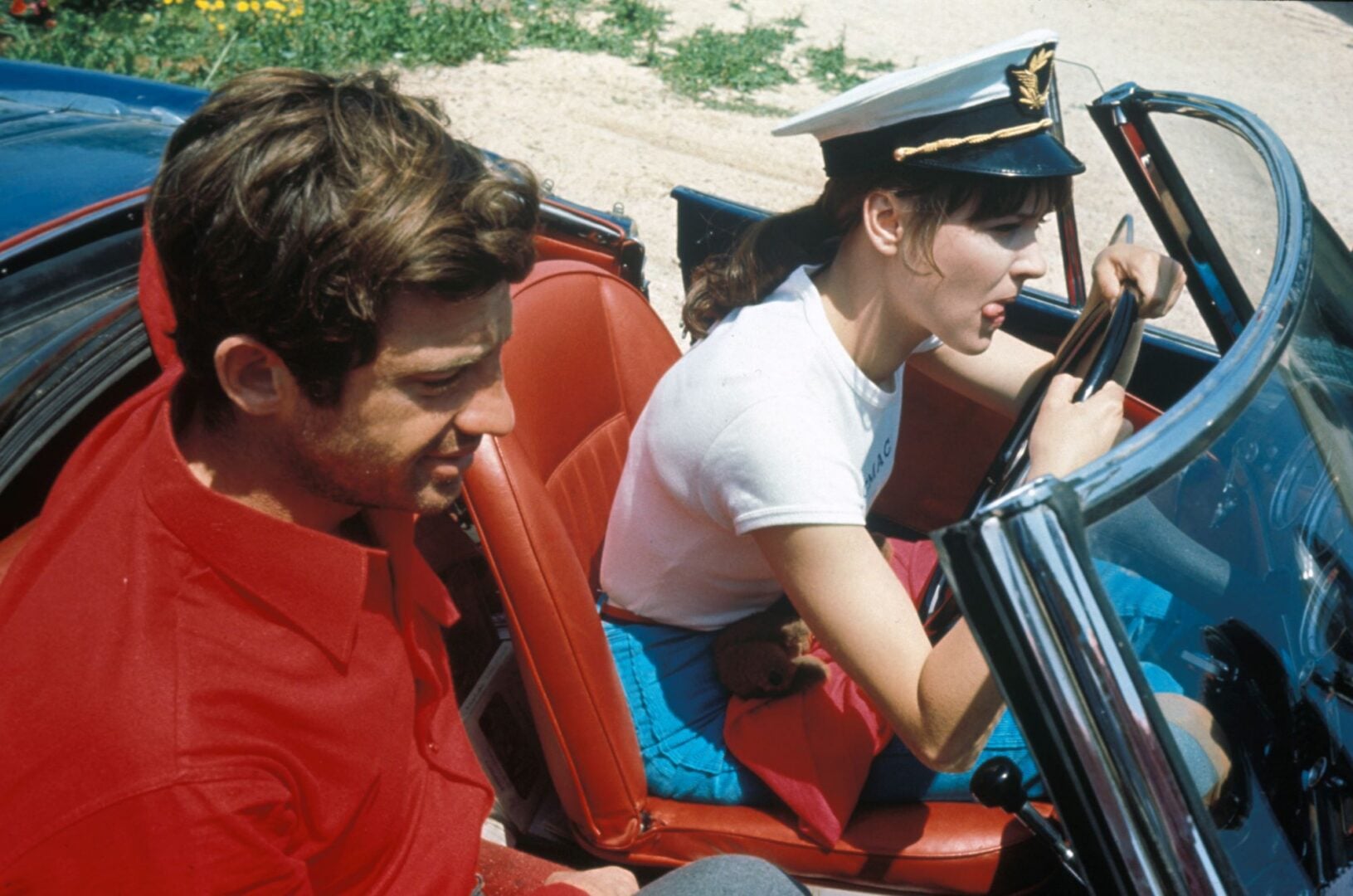 A man and a woman in an open-top car.
