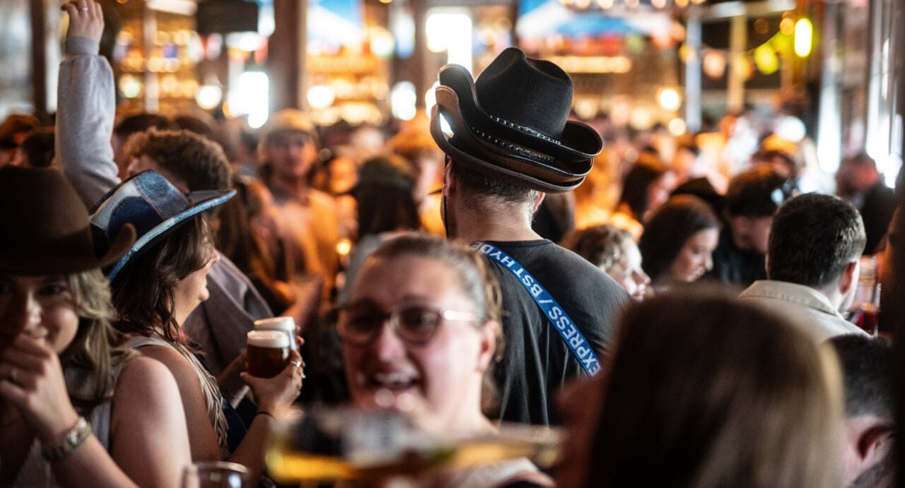 Bar full of people, with several people wearing cowboy hats.